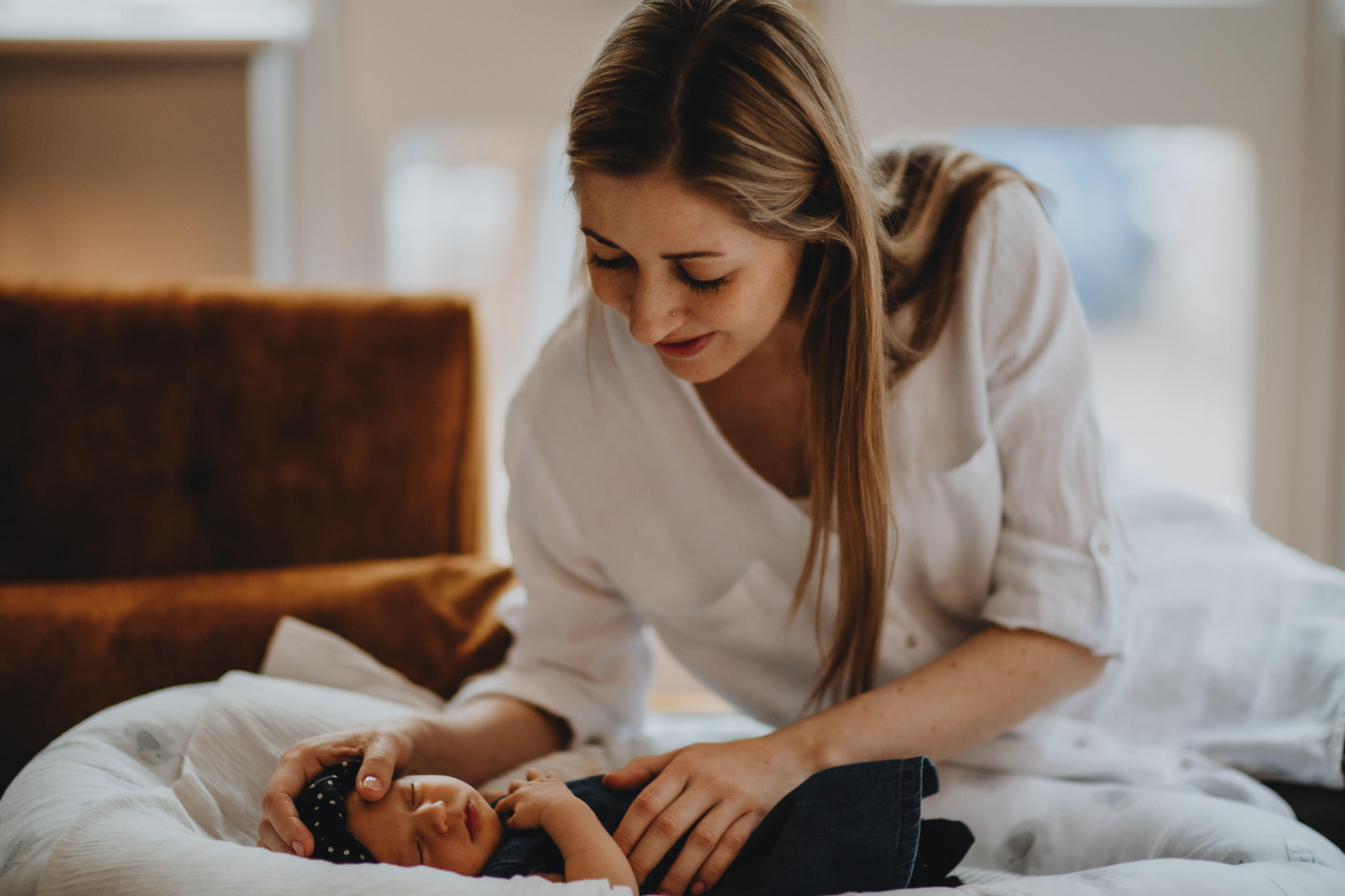 Mum with long hair looking lovingly at her newborn daughter