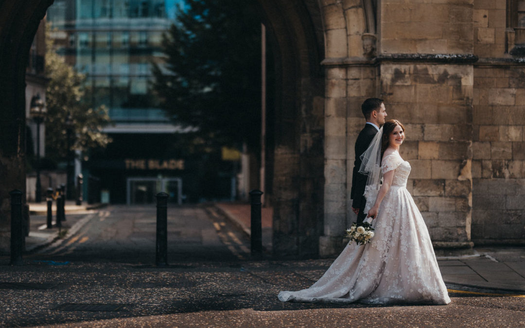 Bride and Groom walking and smiling in front of a sandstone arch