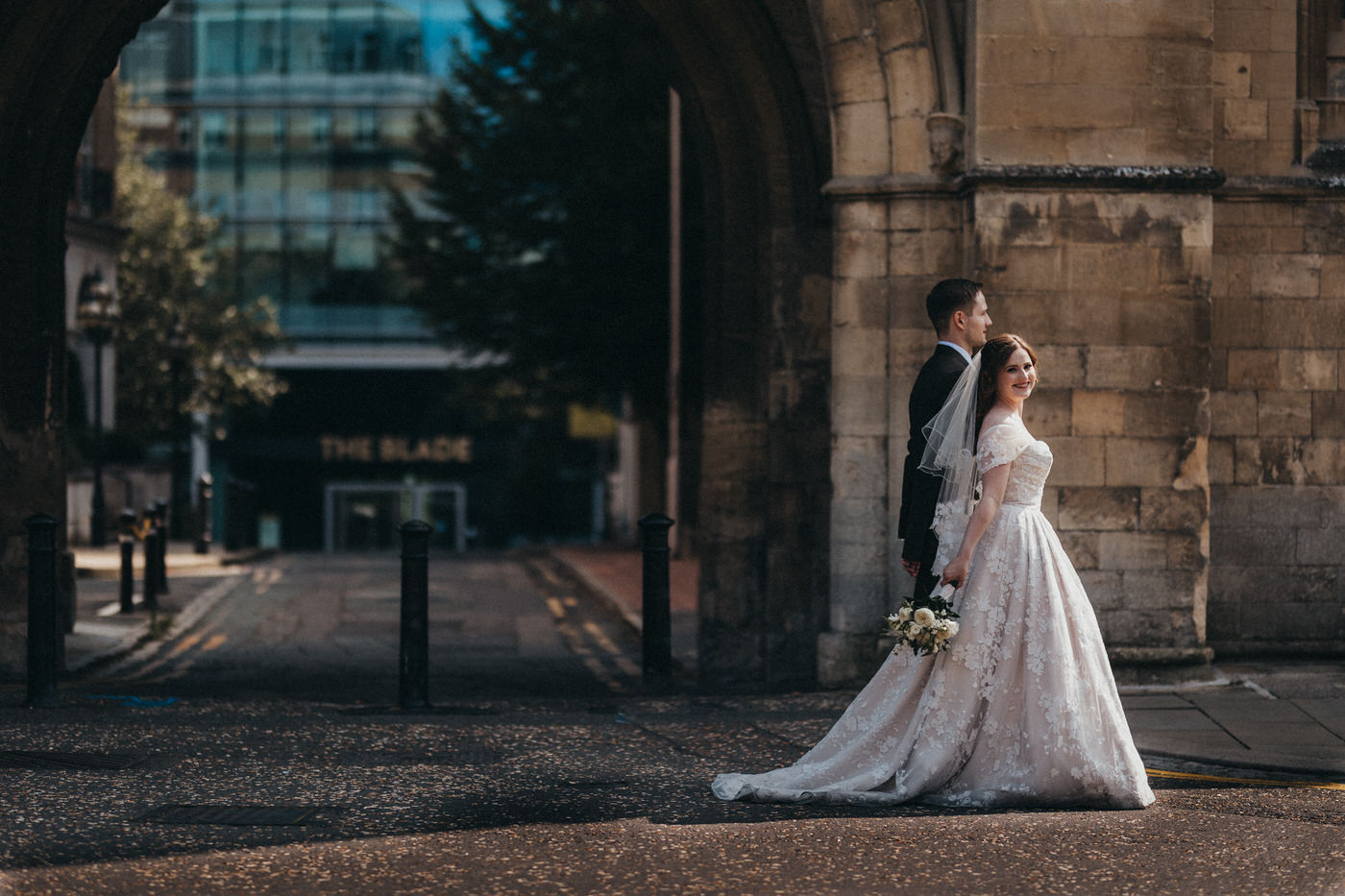 Bride and Groom walking and smiling in front of a sandstone arch