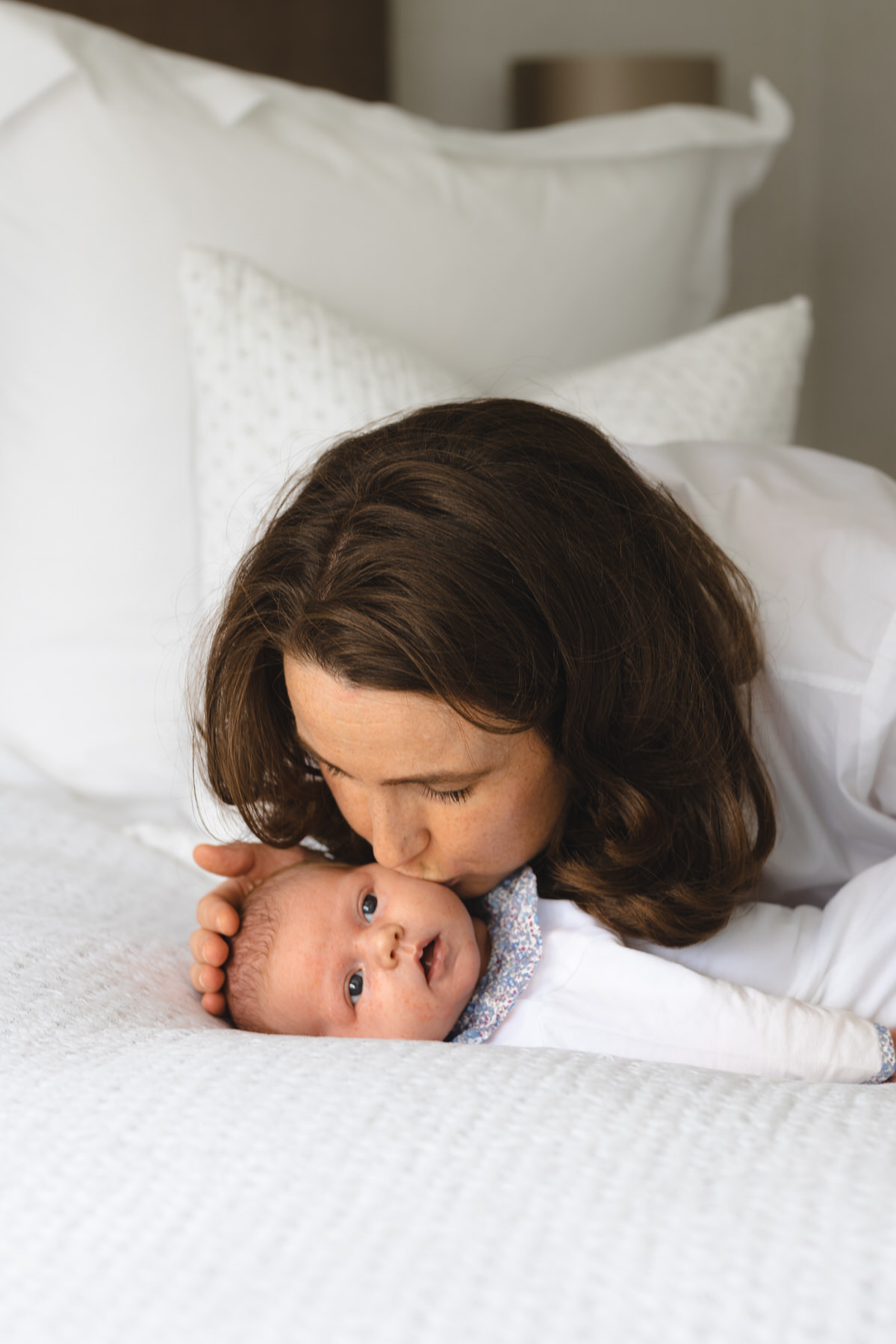 Dark hair mum looking at cute baby kissing her