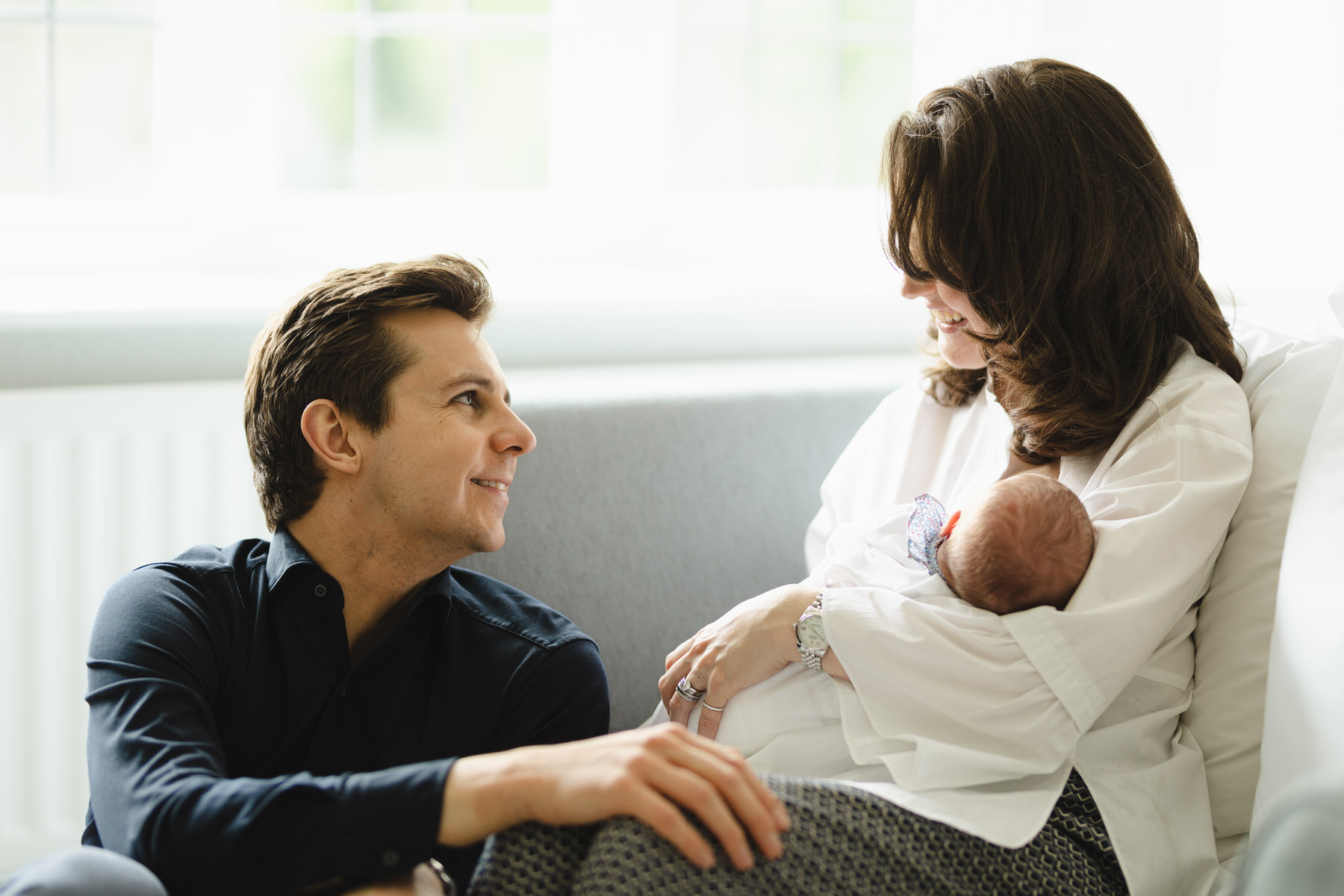 Mother and young son smiling at each other sitting near a water fountain