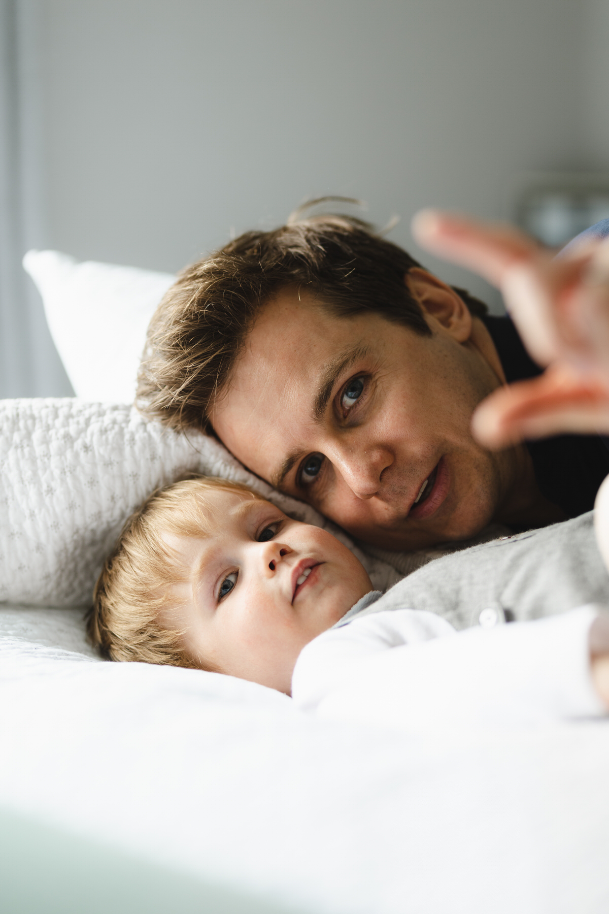 Young Dark haired dad wearing white - playing with son looking at camera