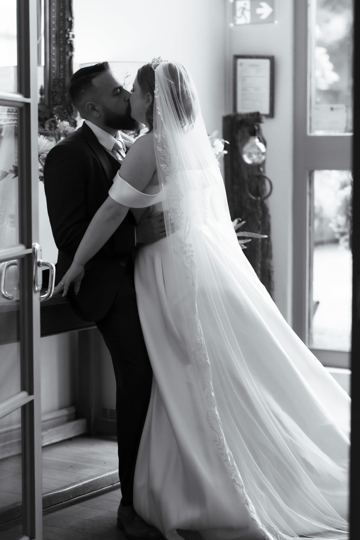 Black and white photo of bride and groom kissing. 